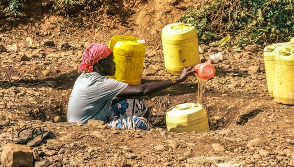 Woman filling water into jericans water from a watering hole in Tangulbei baringo county